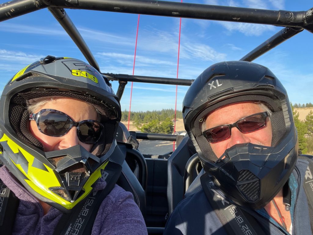 Two people wearing helmets dune riding